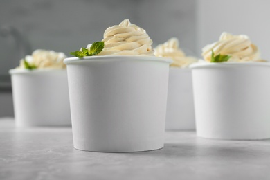 Photo of Cups with tasty frozen yogurt on grey table indoors