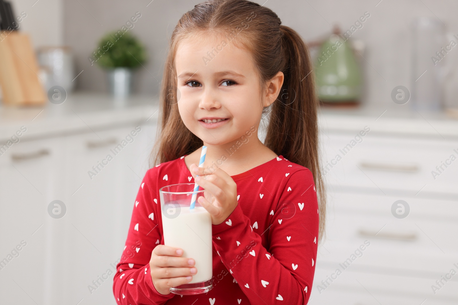Photo of Cute girl with glass of fresh milk in kitchen