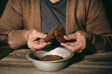 Photo of Poor senior woman with bread at table, closeup