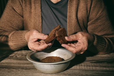 Poor senior woman with bread at table, closeup