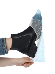 Woman wearing blue shoe cover onto her boot against white background, closeup