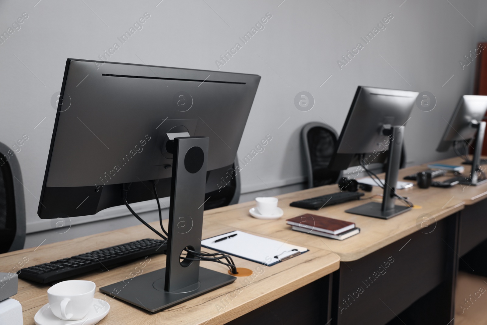 Photo of Open office interior. Modern workplaces with computers near light grey wall