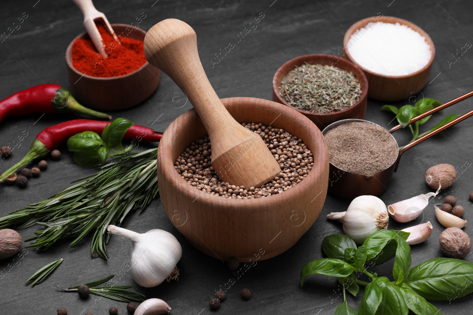 Photo of Mortar with pestle and different spices on black table