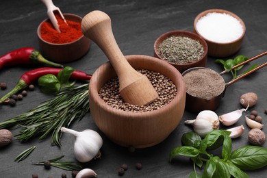 Photo of Mortar with pestle and different spices on black table