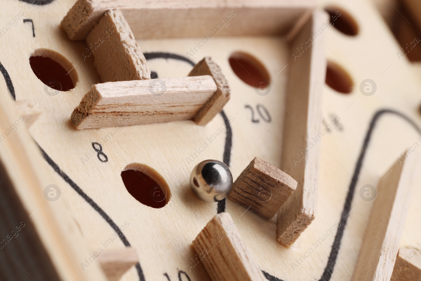 Photo of Wooden toy maze with metal ball, closeup