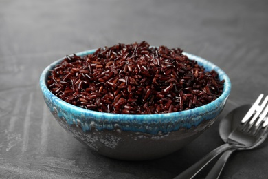 Photo of Bowl with delicious cooked brown rice on grey table