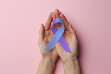 Image of World Arthritis Day. Woman with blue and purple awareness ribbon on pink background, top view