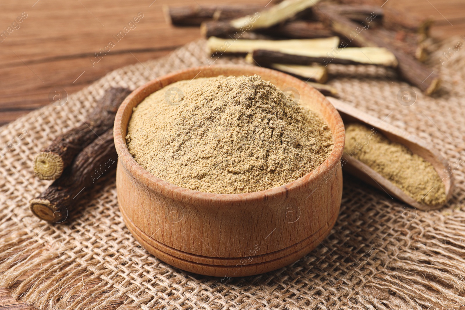 Photo of Dried sticks of liquorice root and powder on wooden table, closeup