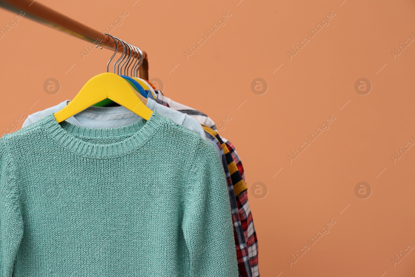 Photo of Rack with stylish children clothes on beige background, closeup. Space for text
