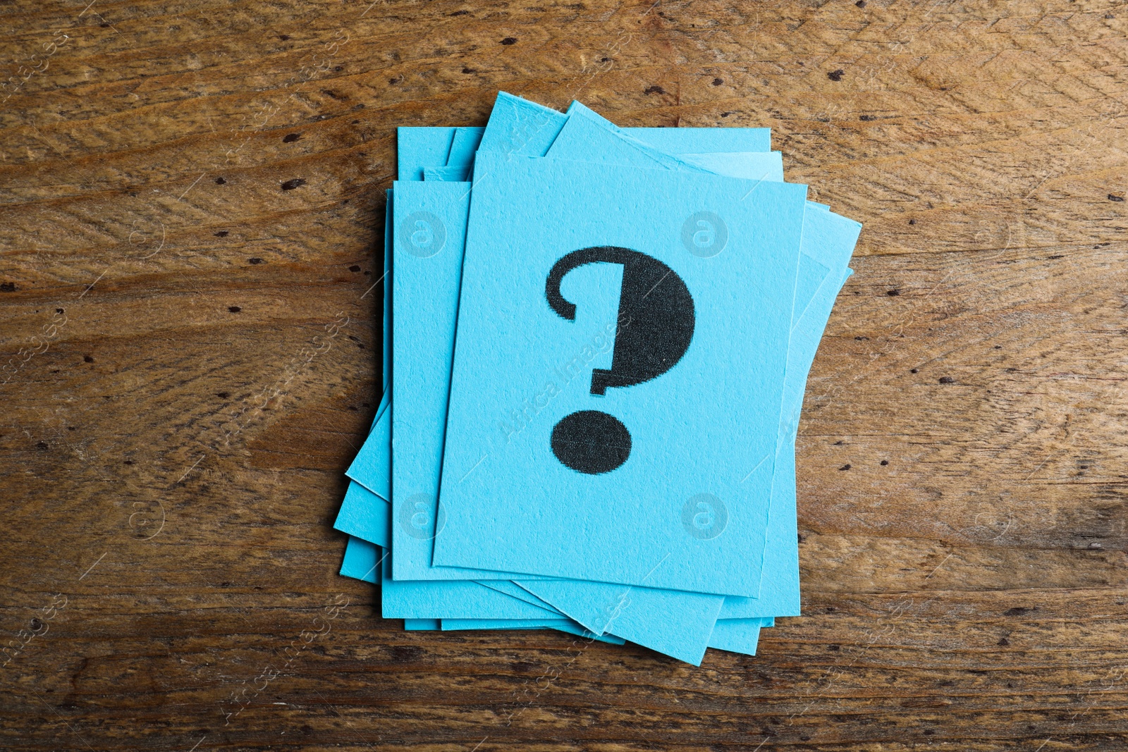 Photo of Blue paper cards with question mark on wooden background, top view