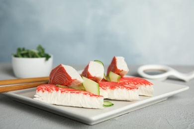 Photo of Fresh crab sticks with cucumber served on grey table, closeup