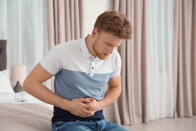 Photo of Young man having nausea in bedroom. Feeling  sick