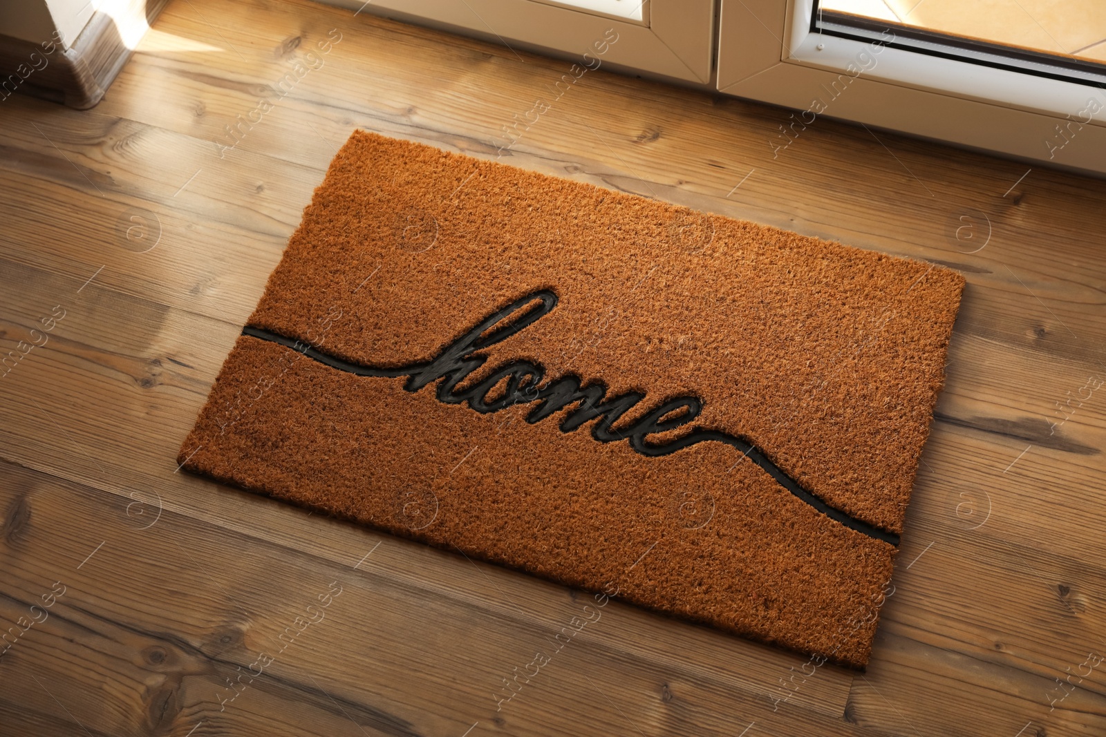 Photo of Doormat with word Home on parquet floor indoors