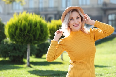 Portrait of happy mature woman with hat in park on sunny day