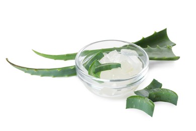 Peeled aloe vera in bowl and pieces of green plant isolated on white