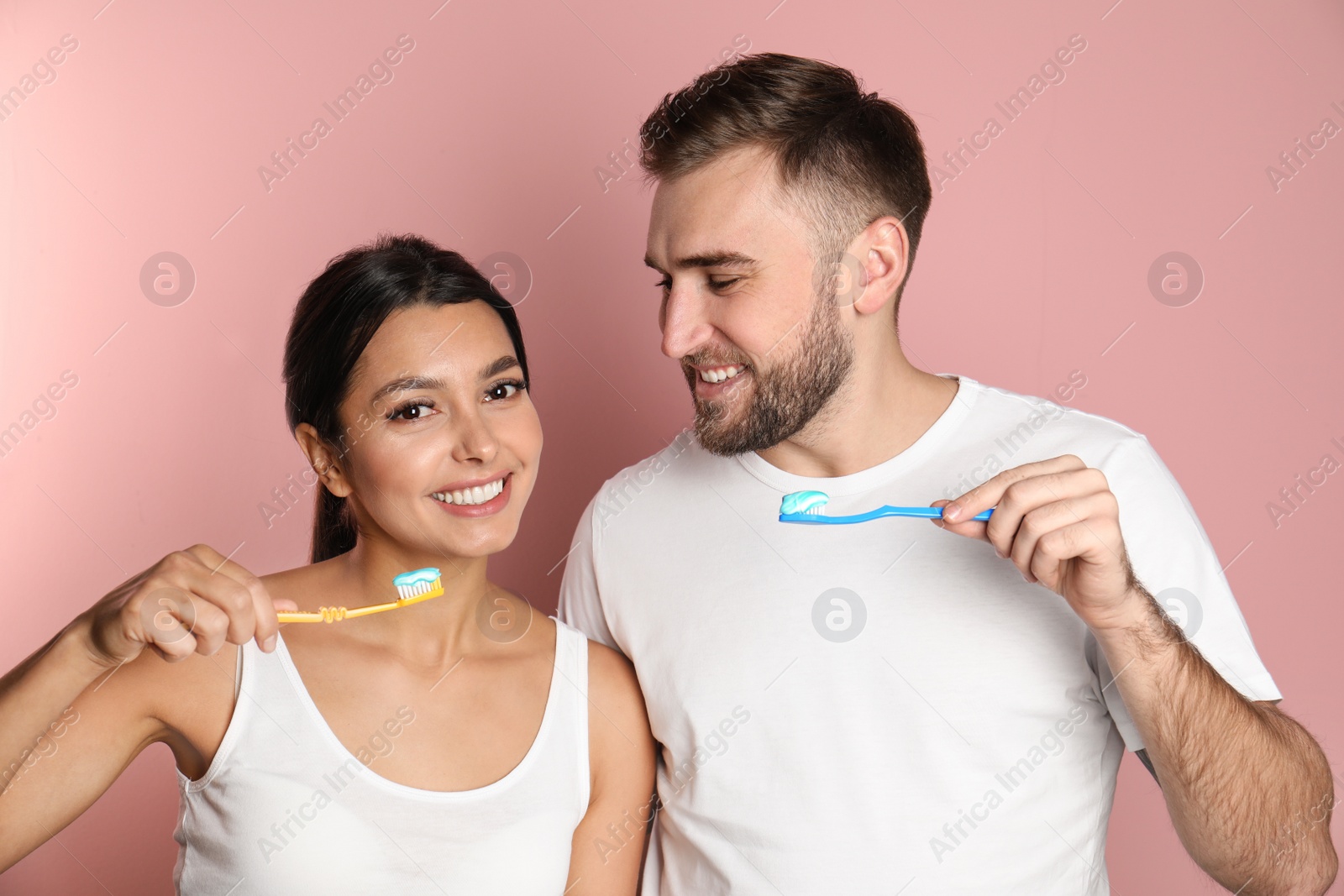 Photo of Young couple with toothbrushes and paste on color background. Teeth care