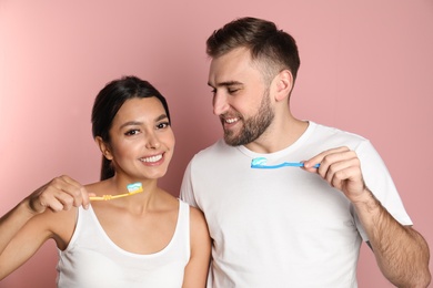 Photo of Young couple with toothbrushes and paste on color background. Teeth care