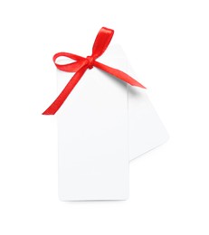 Blank gift tags with red satin ribbon on white background, top view. Space for design