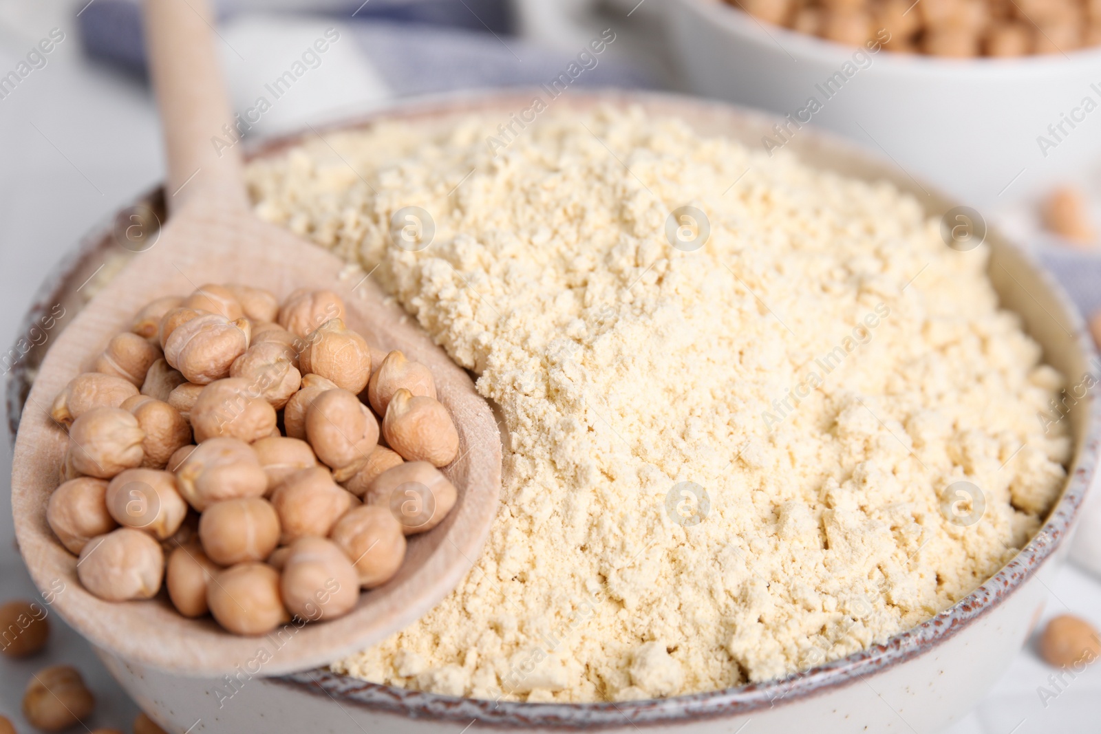 Photo of Chickpea flour in bowl and seeds on table, closeup