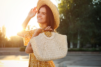 Photo of Young woman with stylish straw bag outdoors