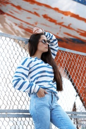 Photo of Young hipster woman in stylish jeans on pier