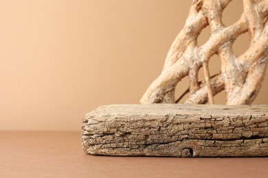 Photo of Presentation for product. Wooden podium and braided tree trunk on beige background. Space for text