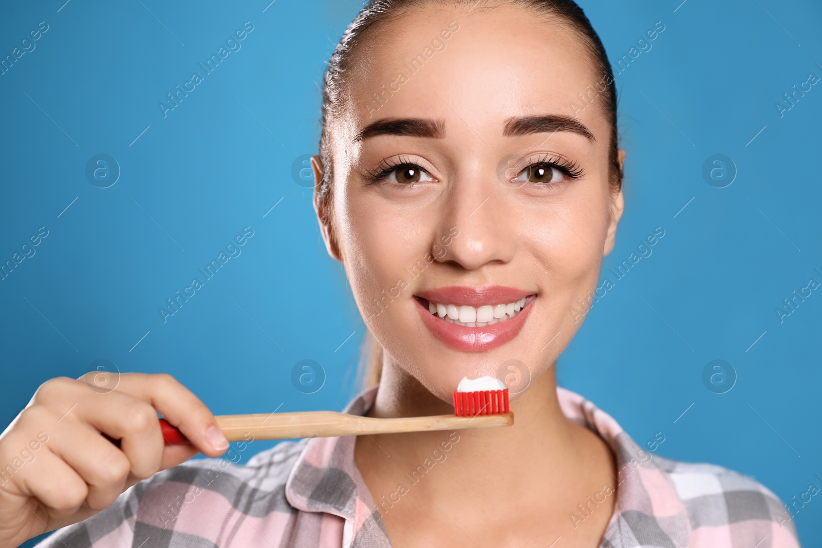 Photo of Woman holding toothbrush with paste on blue background