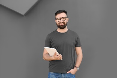 Portrait of young man with tablet near grey wall