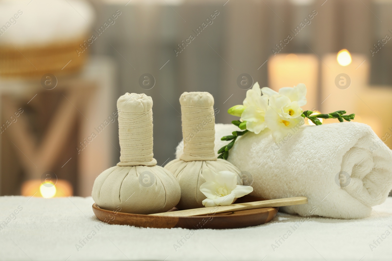 Photo of Beautiful composition with different spa products and flowers on white towel against blurred background