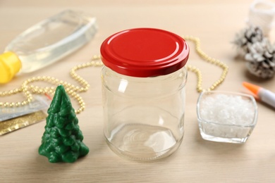 Photo of Glass jar and other elements for handmade snow globe on wooden table, closeup