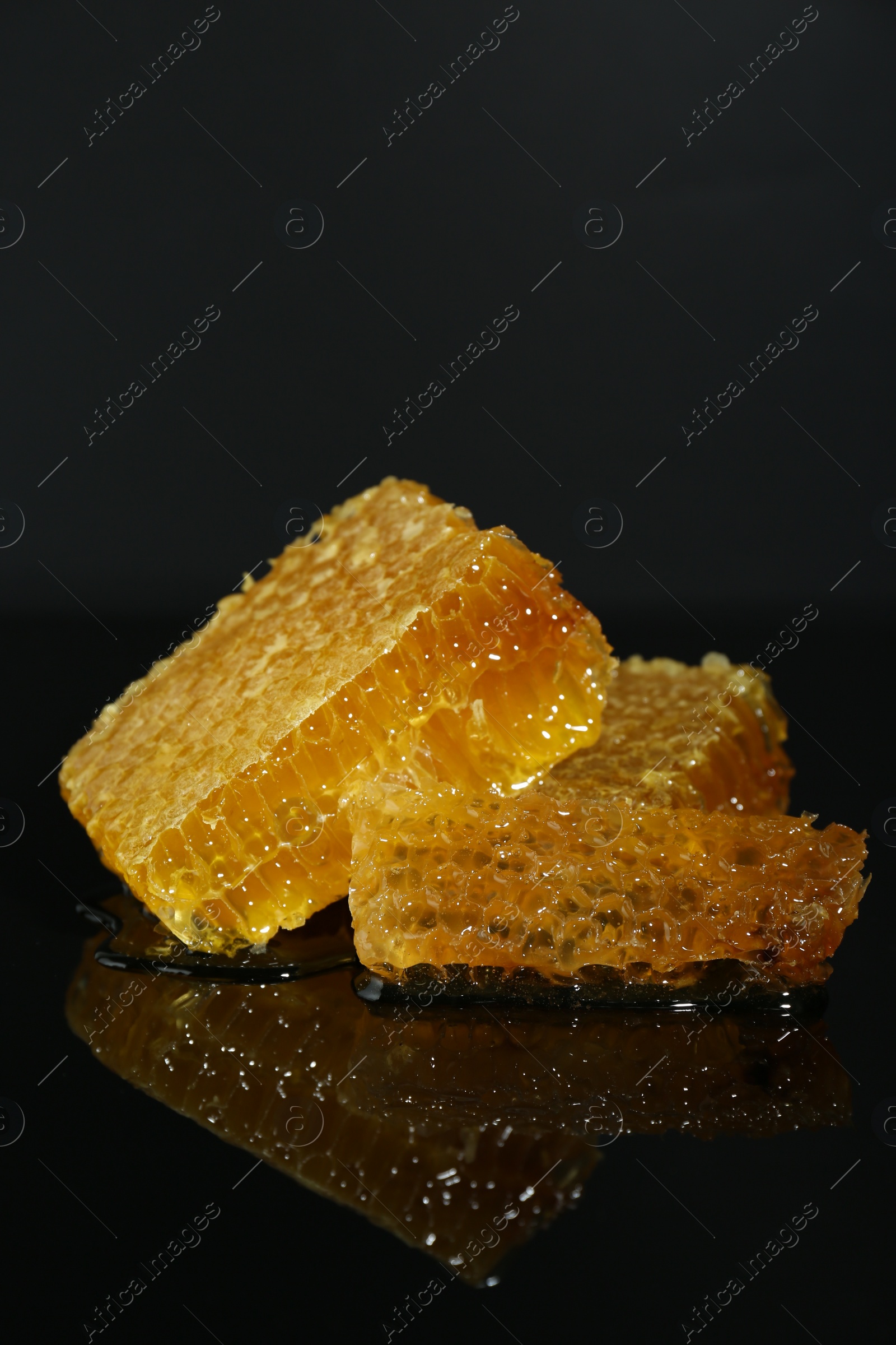 Photo of Natural honeycombs with tasty honey on black background