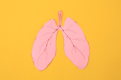 Photo of Paper cutout of human lungs on orange background, top view