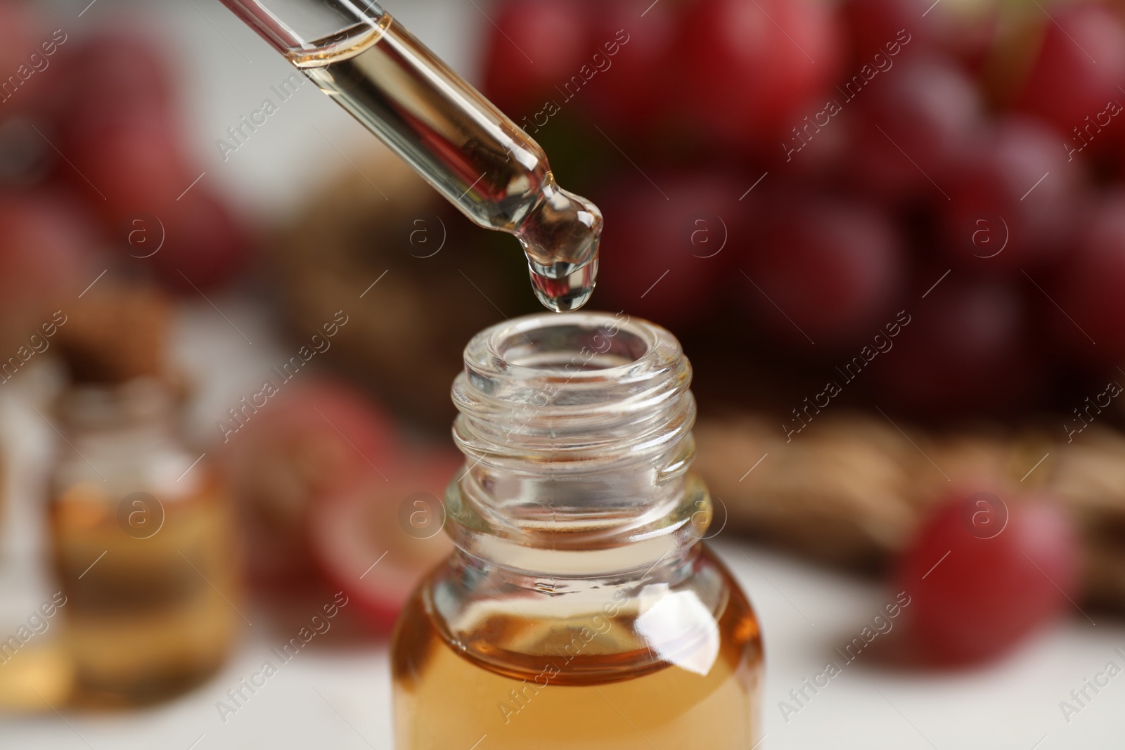 Photo of Dripping natural grape seed oil into bottle, closeup. Organic cosmetic