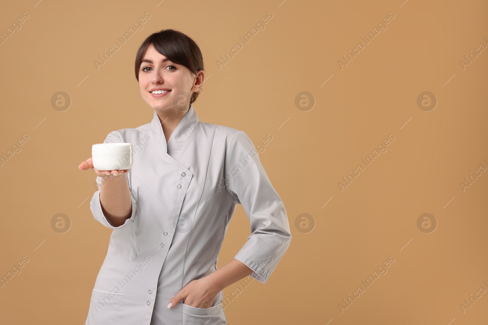 Photo of Cosmetologist with cosmetic product on beige background, space for text