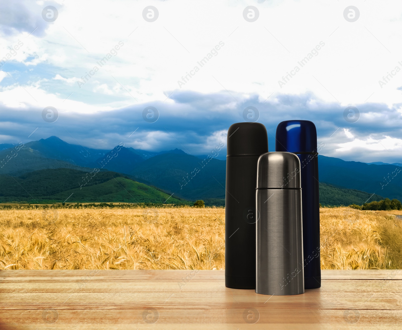 Image of Wooden desk with thermoses and mountain landscape on background