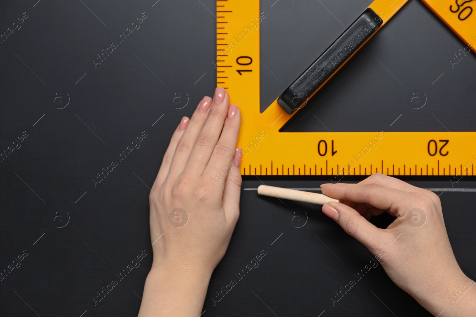 Photo of Woman drawing with chalk and triangle ruler on blackboard, closeup. Space for text