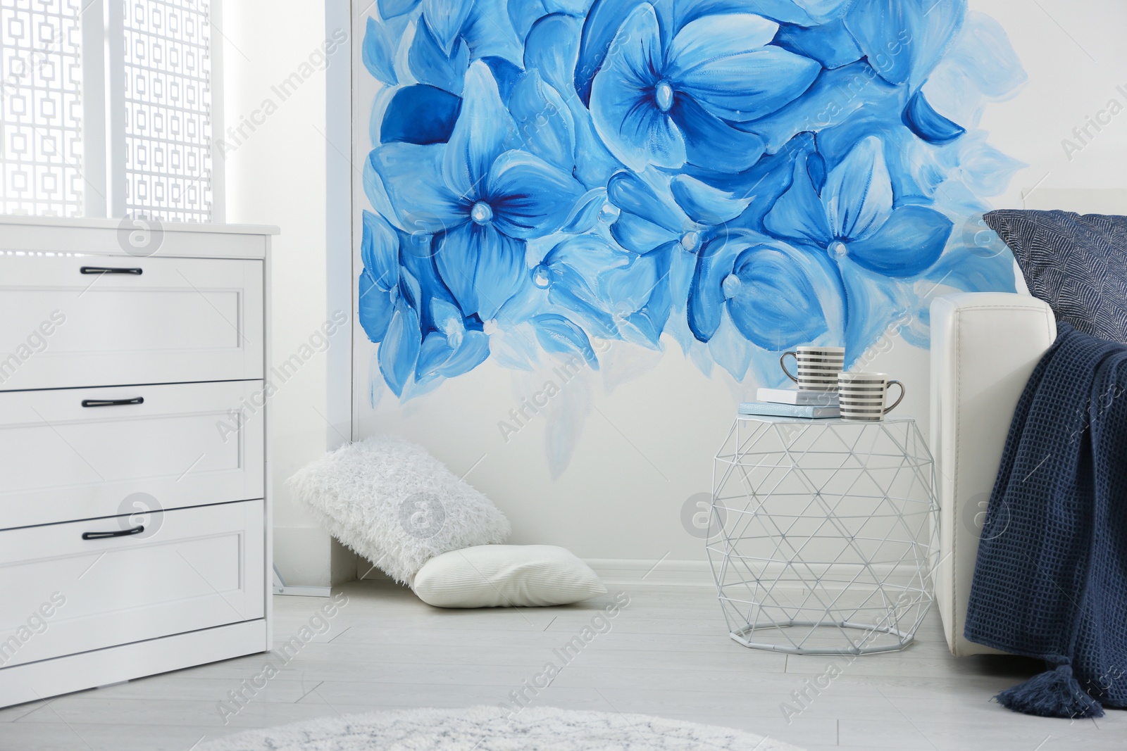 Photo of Stylish living room with blue flowers painted on wall. Floral pattern in interior design