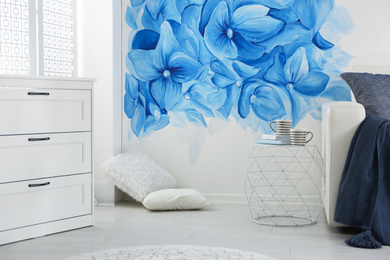 Photo of Stylish living room with blue flowers painted on wall. Floral pattern in interior design