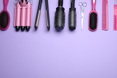 Photo of Flat lay composition of professional hairdresser tools on lilac background, space for text