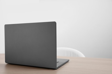 Photo of Stylish modern laptop on wooden table indoors. Space for text