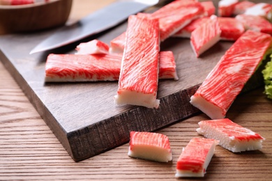 Photo of Delicious crab sticks on wooden table, closeup