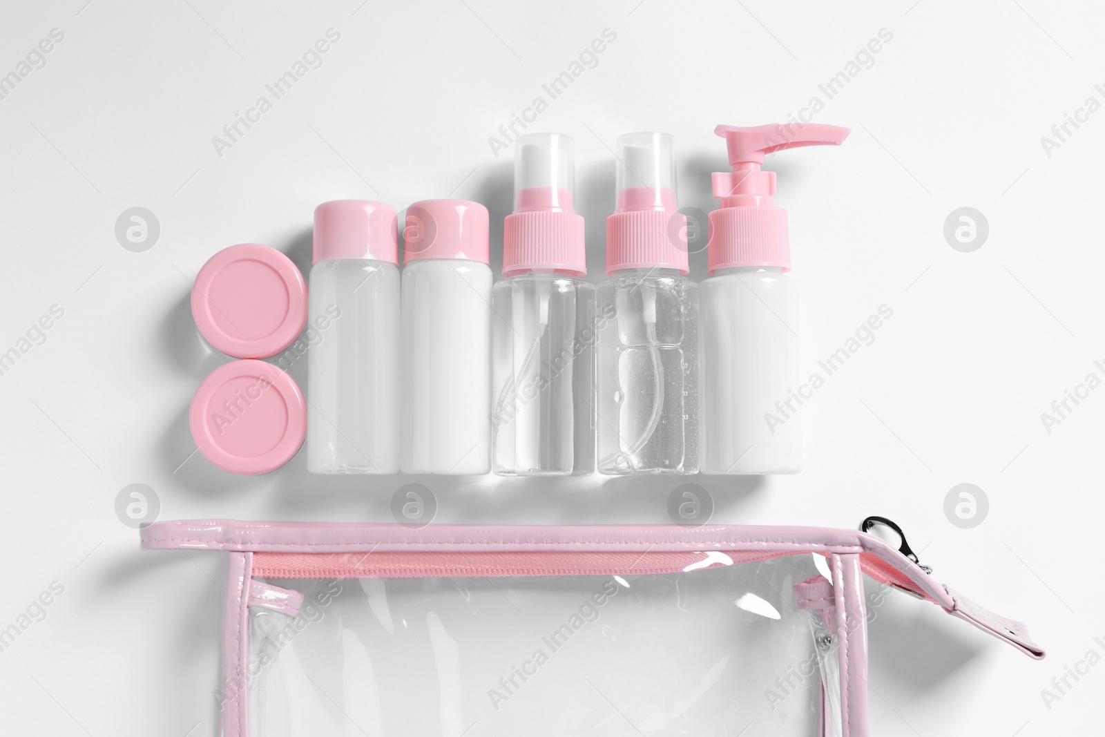 Photo of Cosmetic travel kit and plastic bag on white background, flat lay