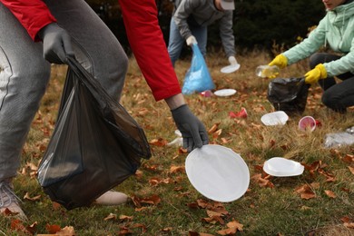Photo of People with trash bags collecting garbage in nature, closeup