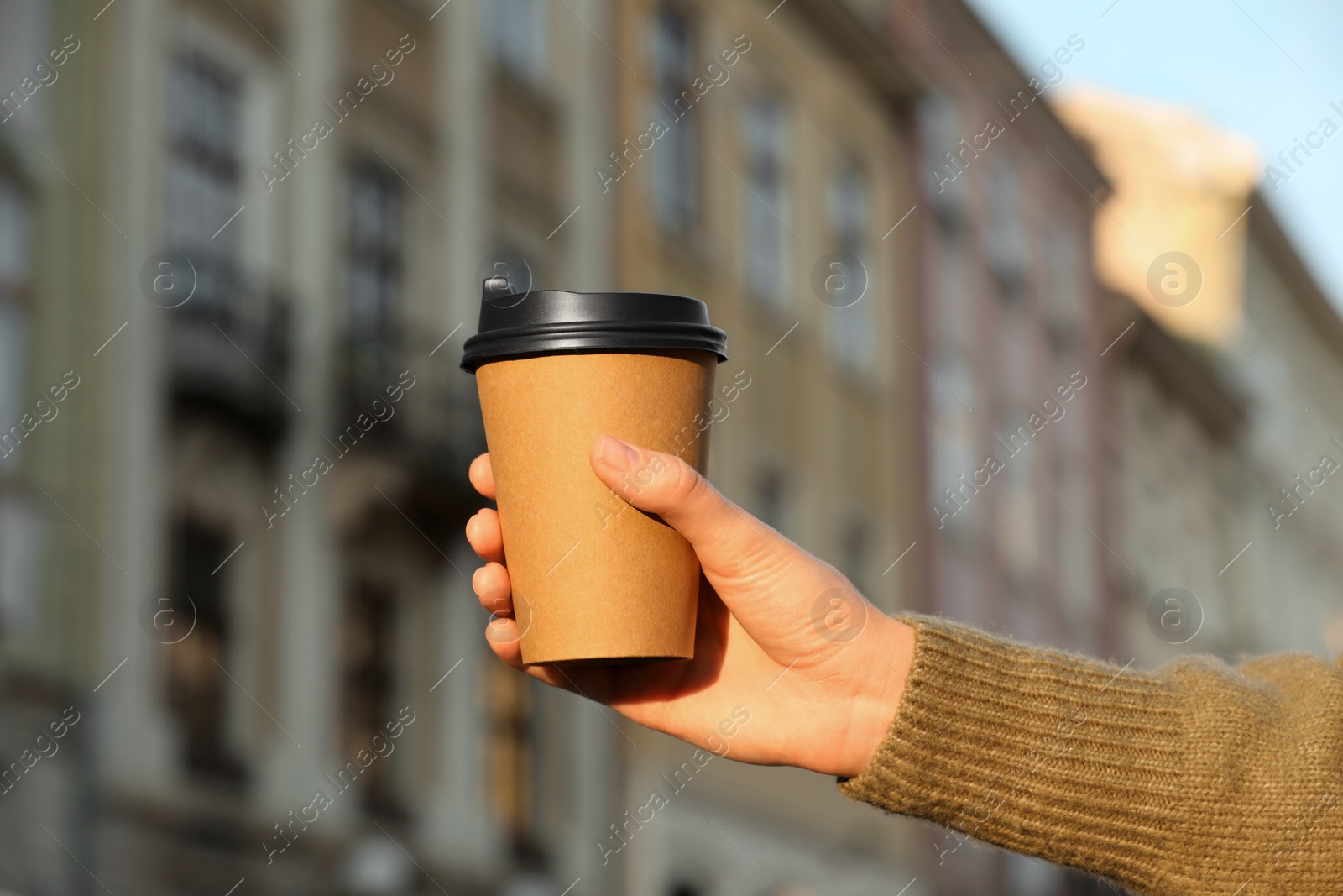 Photo of Woman holding paper takeaway cup outdoors, closeup. Coffee to go