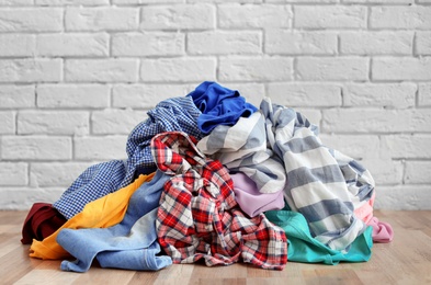 Photo of Pile of dirty clothes on floor near brick wall