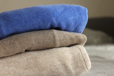 Folded color sweaters on light background, closeup