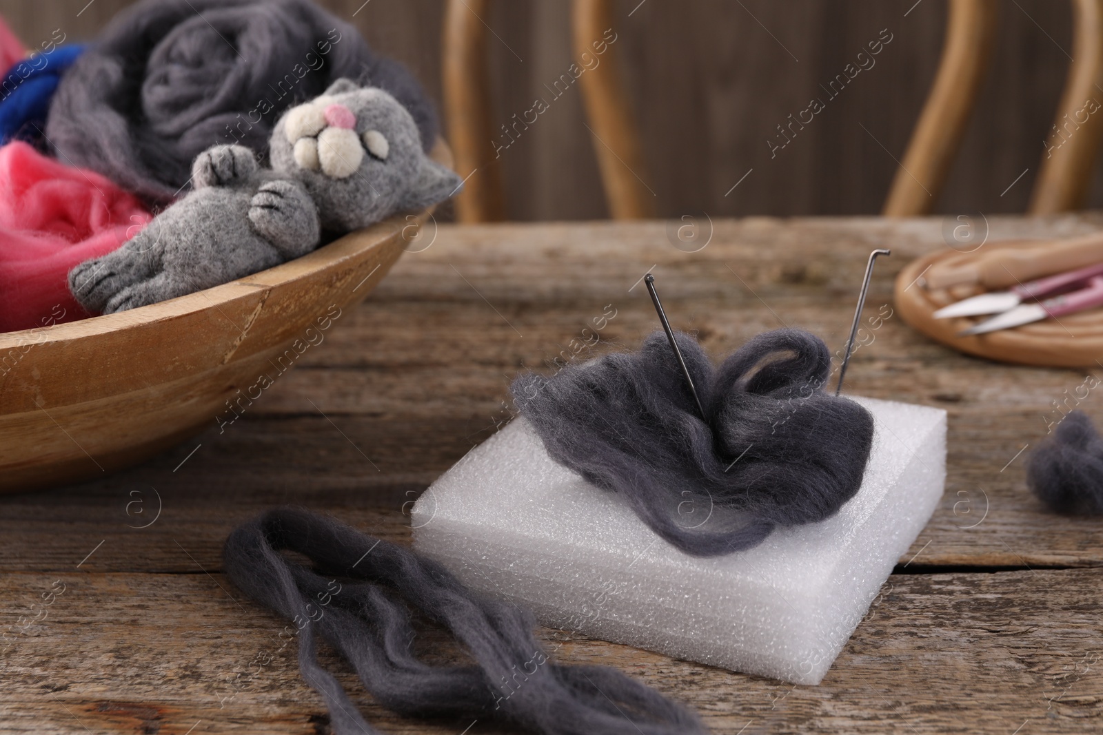 Photo of Felting tools, wool and toy cat on wooden table