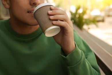 Man with takeaway coffee cup in outdoor cafe, closeup