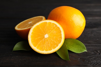 Fresh oranges with leaves on wooden table