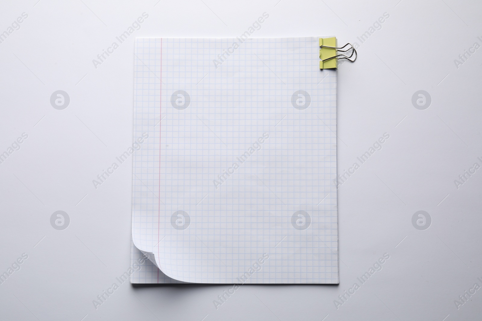 Photo of Checkered paper sheets with binder clip on white background, top view
